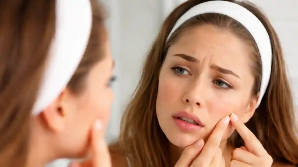Woman checking sudden pimple on face in mirror wondering why do pimples appear overnight